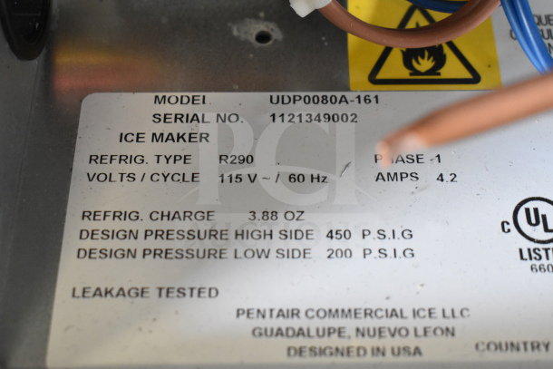Label on Manitowoc UDP0080A-161 ice machine showing model, serial number, refrigerant type, voltage, and design pressure.