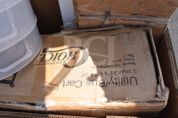 Box containing assorted scratch and dent auction items, including a utility bus cart with visible "Choice" branding and dimensions.