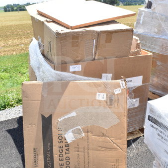 18 new scratch and dent items in boxes, including a Lancaster table, stacked outdoors on a pallet. Tags indicate item details.