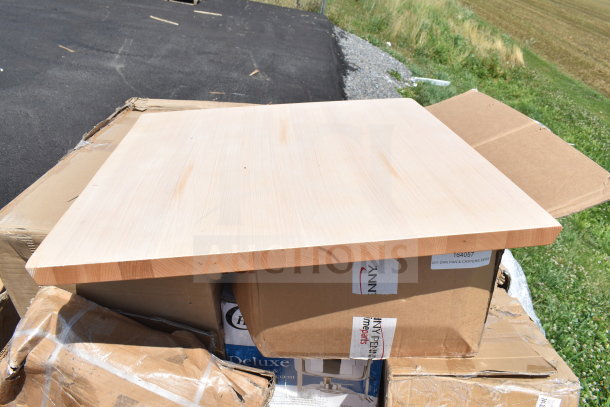 18 brand new scratch and dent items, including a mop sink and chafer, stacked on boxes outdoors; wooden panel on top.