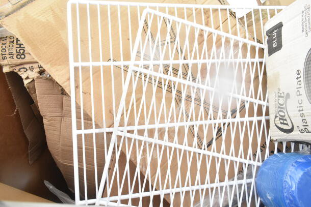 Scratch and dent auction items including white tray stand and Choice 6" plastic plates against cardboard boxes.