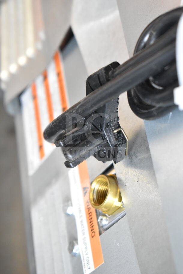 Close-up of a power cord and water inlet on the Manitowoc UDP0065A-161 ice machine, showing warning labels.