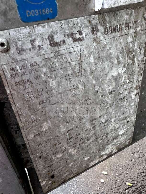 Metal tag on Lucks G1826 commercial natural gas donut fryer shows model and serial numbers, indicating tested operational status.