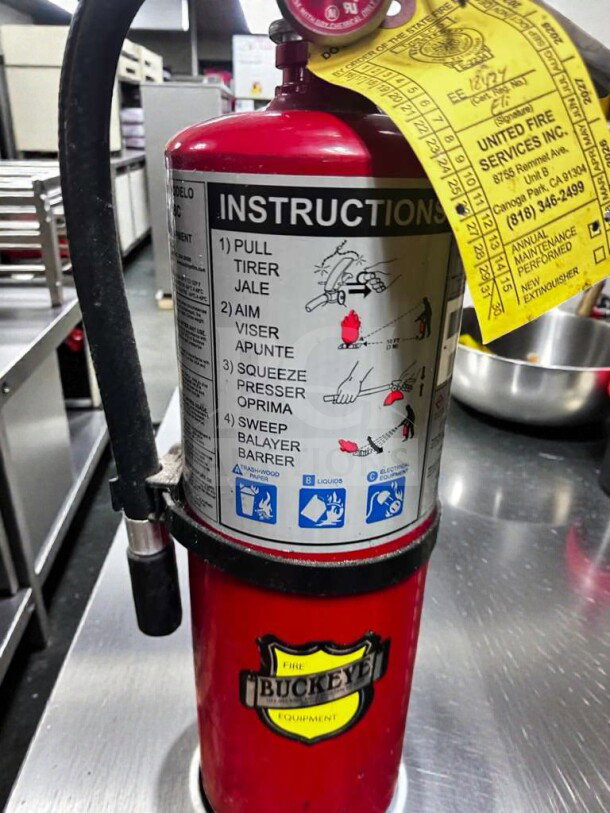Buckeye 5 HI SA40 ABC fire extinguisher, red, UL listed, inspected, operational, instruction label visible, yellow service tag attached.