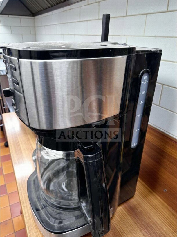 Brand new 12-cup programmable drip coffee machine, stainless steel/black finish, glass carafe, fully operational.