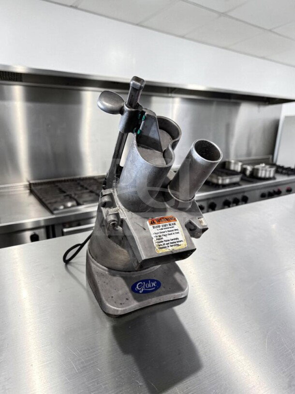 Globe GFP500 food processor, 1/2 HP, 115V, ETL/NSF certified, remarkable condition, fully operational, on stainless steel table.