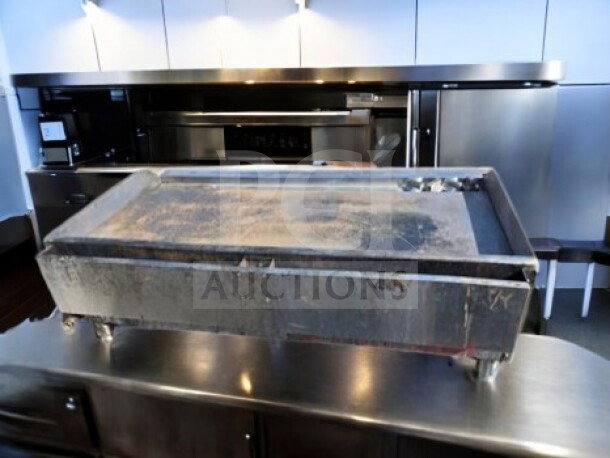 Commercial griddle, Globe GG48G model, on stainless steel surface, shows wear. Ideal for high-volume cooking tasks.