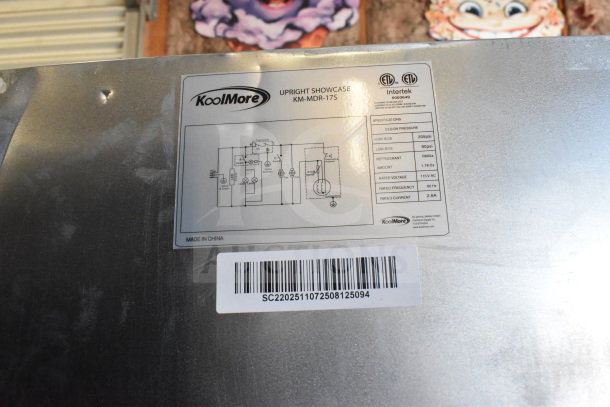 KoolMore KM-MDR-17S label showing specs and barcode. New slim commercial merchandiser fridge, 7 cu. ft., black. Minor dent visible.
