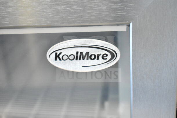 KoolMore KM-MDF46GD logo on a stainless steel surface, indicating the 24-inch commercial display freezer.