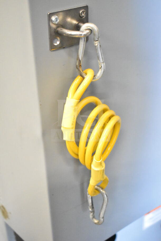 Alt text: Yellow safety tether attached to Pitco Frialator gas fryer, secured with metal carabiner, indicating safety feature.
