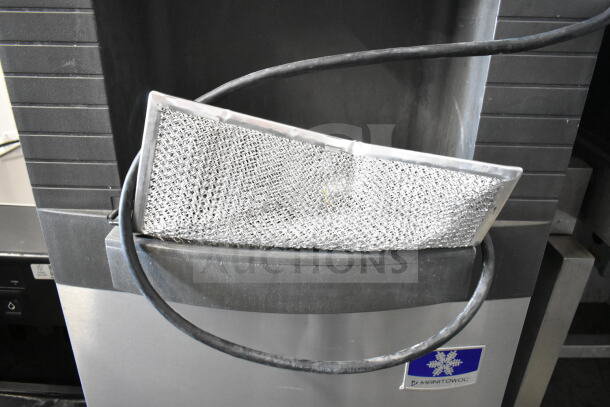 Manitowoc commercial ice head on hotel ice dispenser. Stainless steel, fair condition, visible Manitowoc brand logo.