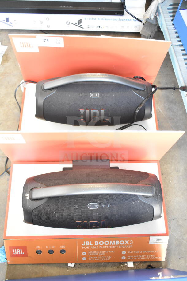 Two JBL Boombox 3 speakers in store display; features include massive sound, waterproof design, and 24-hour playtime.