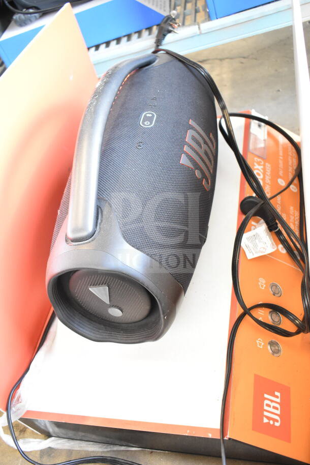 JBL Boombox 3 speaker display on an orange base. Features prominent JBL logo, handle, and control panel. Cords included.