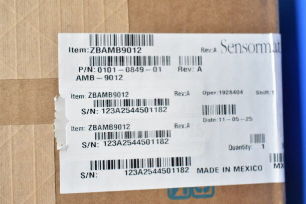 Sensormatic ZBAMB9012 label showing P/N 0101-0849-01, S/N 123A2544501182, made in Mexico, on a cardboard box.