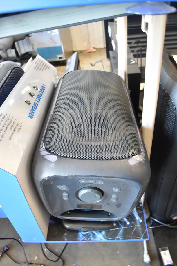 3 Onn large party speakers on display, featuring control dials and mesh grills. Visible text indicates product features.