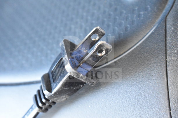 Close-up of a power plug, possibly from the Onn Large Party Speaker, showing two metal prongs with the marking "GEIM."