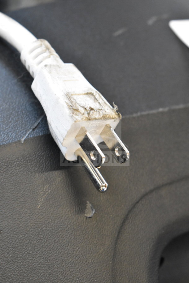 Damaged white power plug on black textured surface, part of store display including Ion Pro Glow Ultra Speaker.