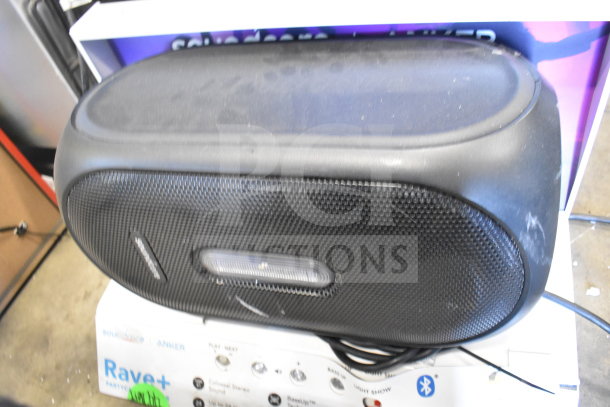 Black Rave+ speaker display on box. Features include play next buttons, Bluetooth, and party lighting. Slight wear visible.