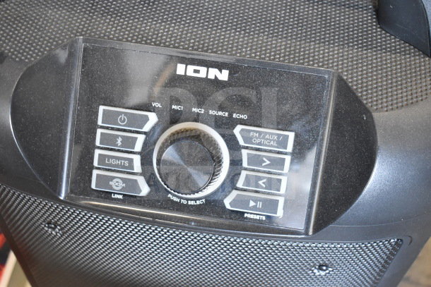 Ion speaker control panel featuring volume, mic, and source buttons. Slight wear visible, includes FM/AUX options.