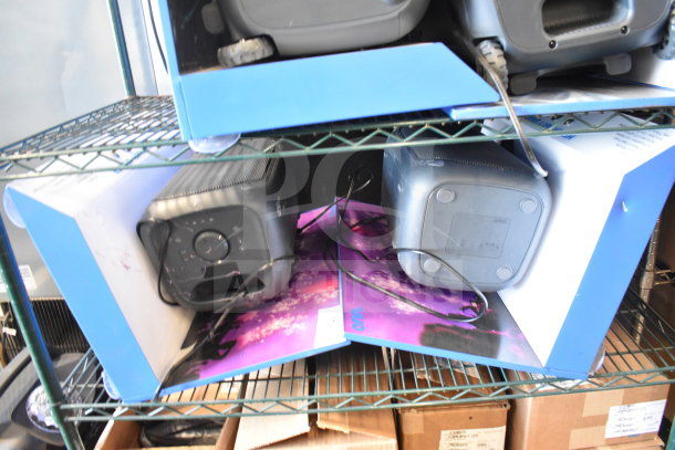 Two Onn Medium Party Speakers in original packaging on a metal shelf. Features include control dials and connectivity ports.