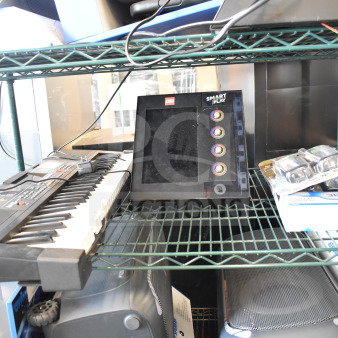 Four items on a shelf: electronic keyboard, Lego Smart Play device, packaged walkie talkies, and a box.