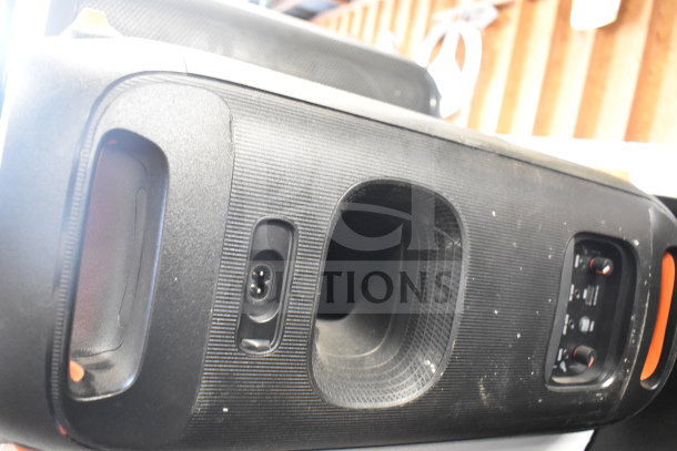JBL speaker with textured black exterior, visible control panel, and power input on store display. Slight wear shown.