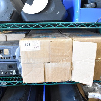 Shelf with Sensormatic ZBSMPROE and other electronics. Items are boxed; visible labels indicate lot number 105, qty X-7V.