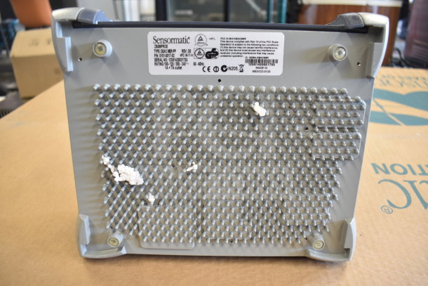 Sensormatic ZBSMPROE device; used with label showing model info. Base has noticeable wear with residue attached.