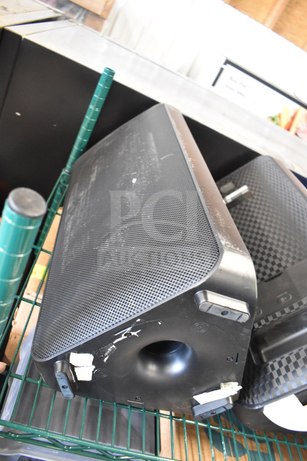 Three store display speakers, including a Samsung speaker and an Onn large party speaker, shown on a green metal shelf.