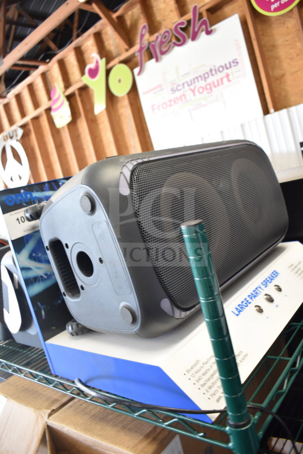 Samsung speaker and Onn large party speaker displays on a shelf. Both in good condition, demonstrating features for store use.