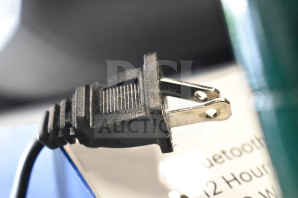 Close-up of a black power plug next to a blurred product label. Part of an auction featuring Samsung and Onn speakers.