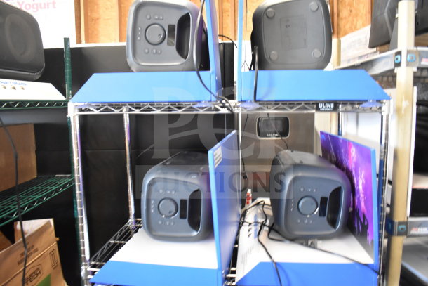 Four Onn medium party speakers on store display shelves, showing front controls and black finish. Cables visible, new condition.