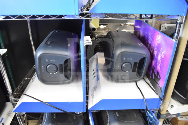 2 store displays with Onn Medium Party Speakers, black, showcasing front controls. Clean condition, promotional setup.