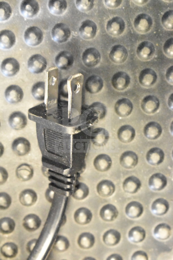 Power cord with a two-prong plug against a dotted textured background, part of store display for Onn Medium Party Speaker.