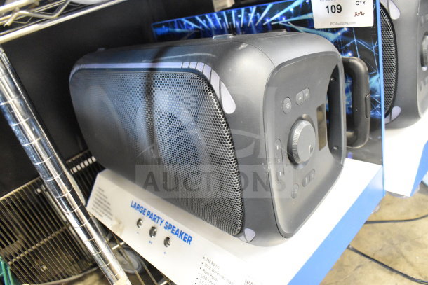 Pair of store displays with Onn Large Party Speaker, black, visible control panel and carrying handle, item tag stating "Large Party Speaker."