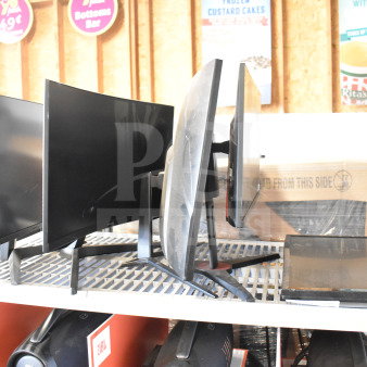 Five various monitors including Vizio, Onn, MSi, Samsung, on a shelf. Mixed sizes, black frames, used condition.