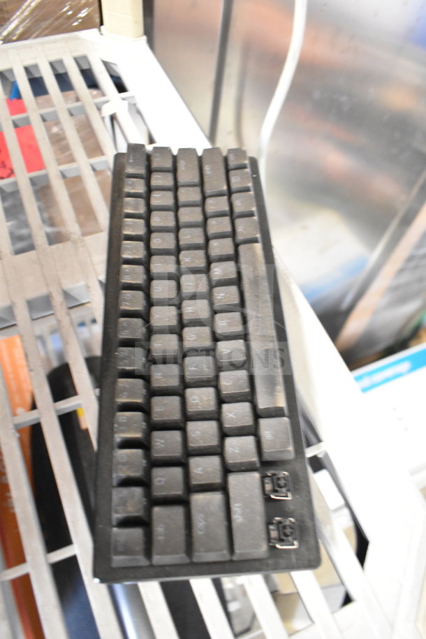 Dusty black keyboard with missing keys on metal shelving. No visible tags or labels; not related to the auction item.