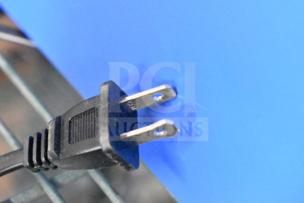 Power plug connected to a blue panel, part of the Onn Medium Party Speaker store display.