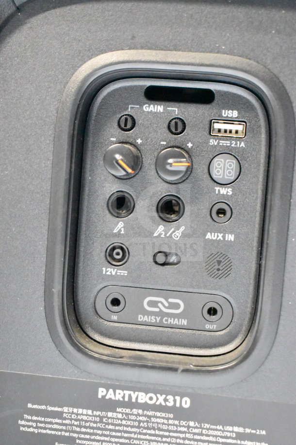 Close-up of JBL PartyBox 310 speaker control panel showing gain knobs, USB port, AUX inputs, and daisy chain option.