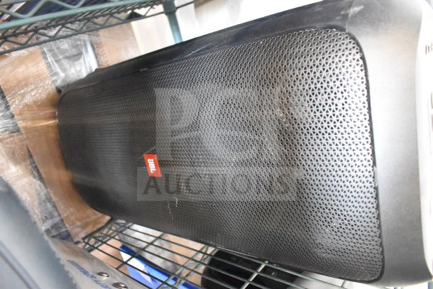JBL PartyBox 310 speaker, black mesh grille, excellent condition, red JBL logo, showcased on metal shelving.