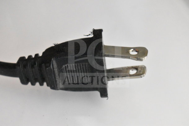 Close-up of a black electrical plug in used condition, showing metal prongs and textured grip, part of auction items.