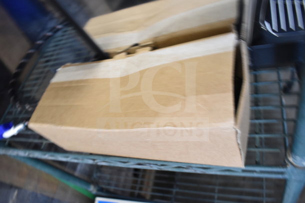 Cardboard box on a metal shelf, containing a Nuova Simonelli OSCAR II AD espresso machine. Box closed, condition unknown.