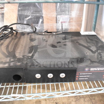 Black JBL speaker store display unit with multiple control buttons, power cord, and promotional labels. Visible dust and minor wear.