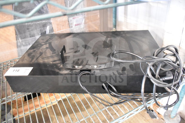 Black JBL speaker store display unit with attached cables, minor scuffs, and a visible label marked "118" on a metal shelf.