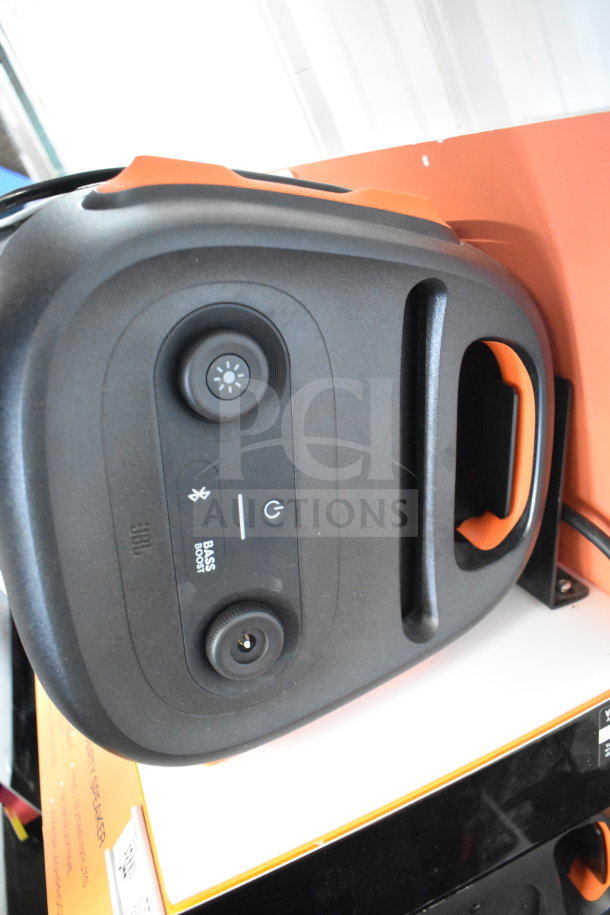 JBL PartyBox 110 Speaker display. Features bass boost, power, and Bluetooth buttons. Black, orange accents, store use.