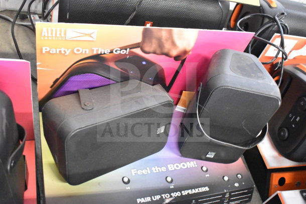 Altec Lansing speaker display, featuring two black speakers with handles, promotional signage. Ideal for portable audio setups.