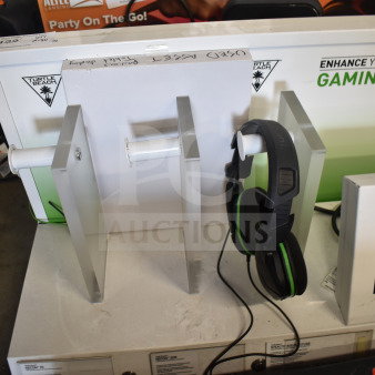 Store display featuring Turtle Beach gaming headset, LG soundbar, and screen. Signs of use; headset mounted on stand.