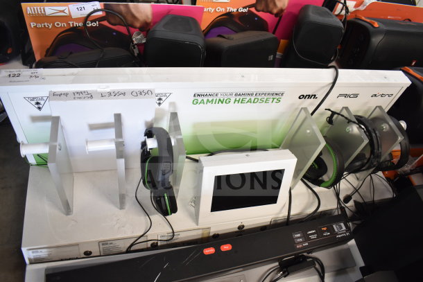 Store display featuring gaming headsets and screen, LG soundbar included. Brands: Onn, RIG, Astro. Used condition, visible labels.