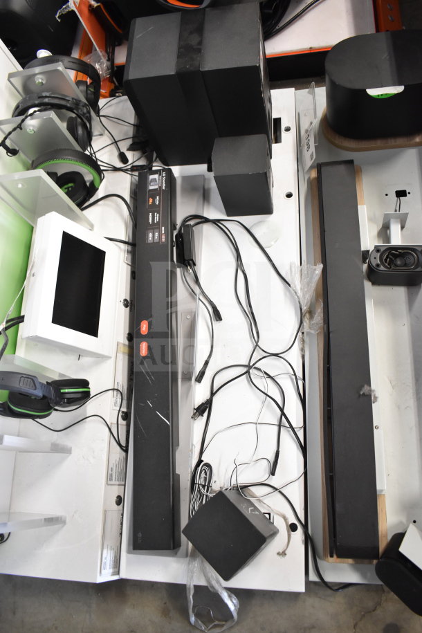 Store display featuring gaming screen, headphones, and LG soundbar. Includes cords and accessories, overall used condition.
