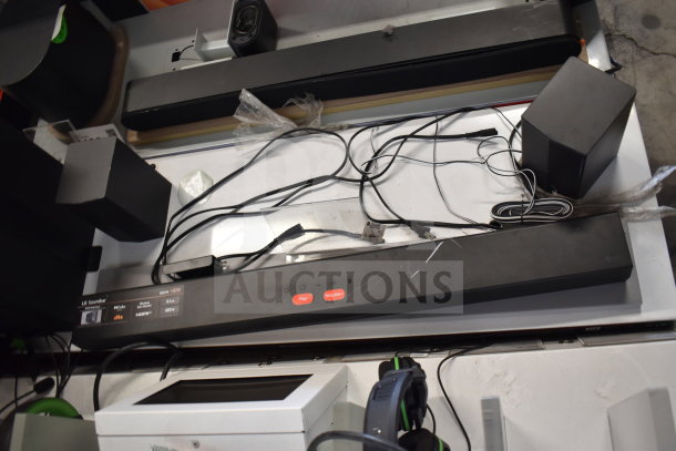 3 store display includes gaming screen, headphones, and LG soundbar. Cables visible. Condition appears used.